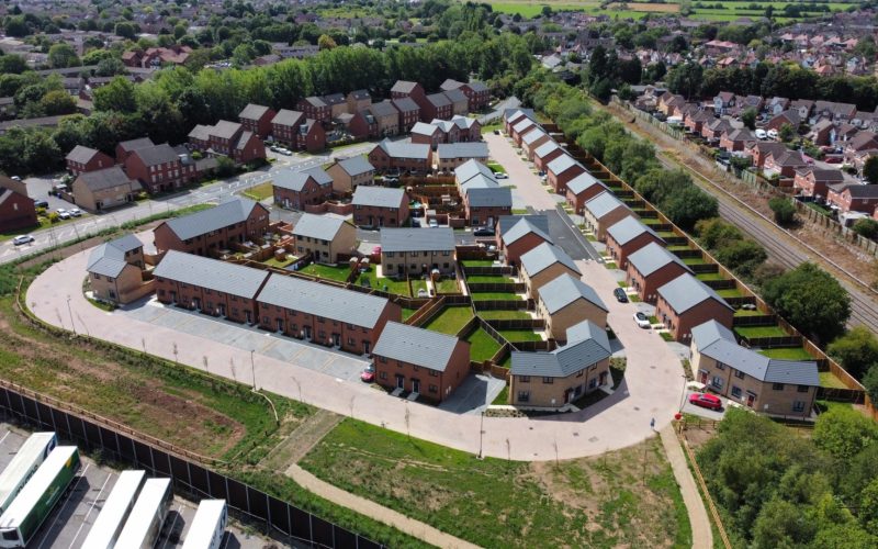Aerial view of a newly built housing estate with rows of homes and surrounding roads.