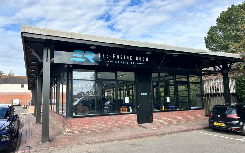 The Engine Room fitness facility at Station Approach, Chichester, with dark glass frontage and cars parked outside.