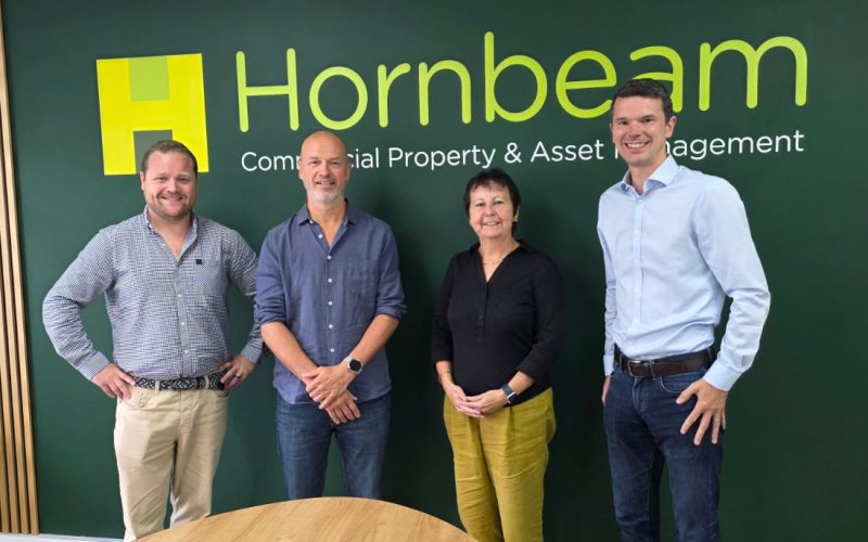 Four Hornbeam team members pose in front of the company’s Commercial Property & Asset Management sign.