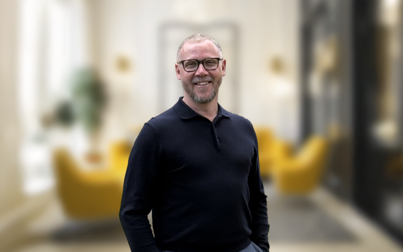 Iain Powis, Savills associate director, smiling in a black shirt in a blurred office