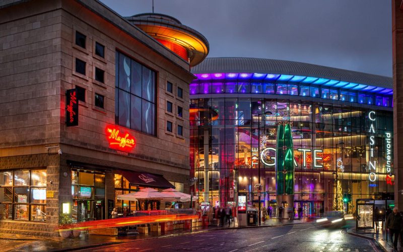 Architectural rendering of a modern entertainment complex with a cinema, shops and illuminated streetscape