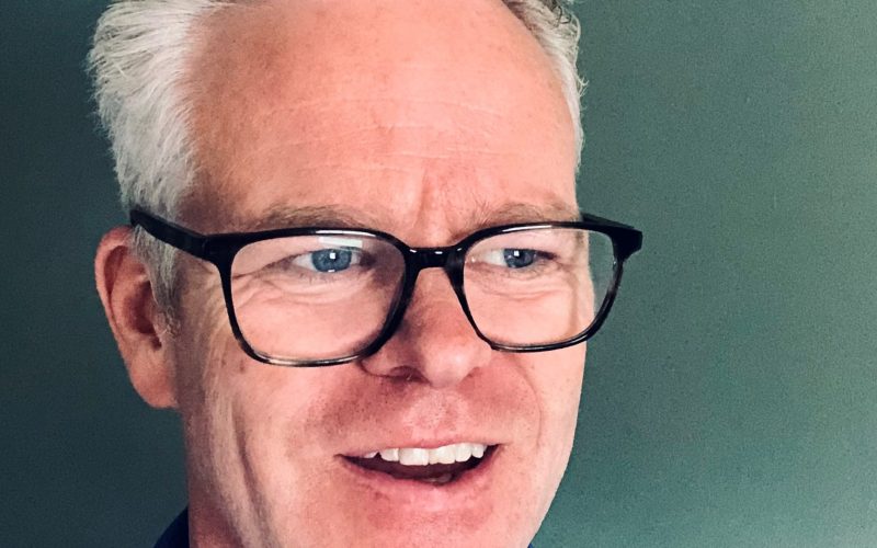 Andrew Stanford, a man with short gray hair and black glasses, smiles at the camera.