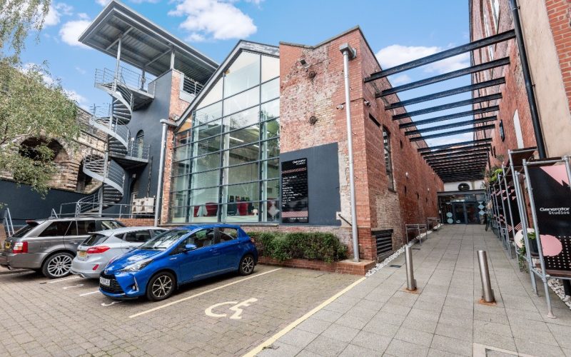 Modern commercial property with glass-fronted entrance, covered walkway and parked cars
