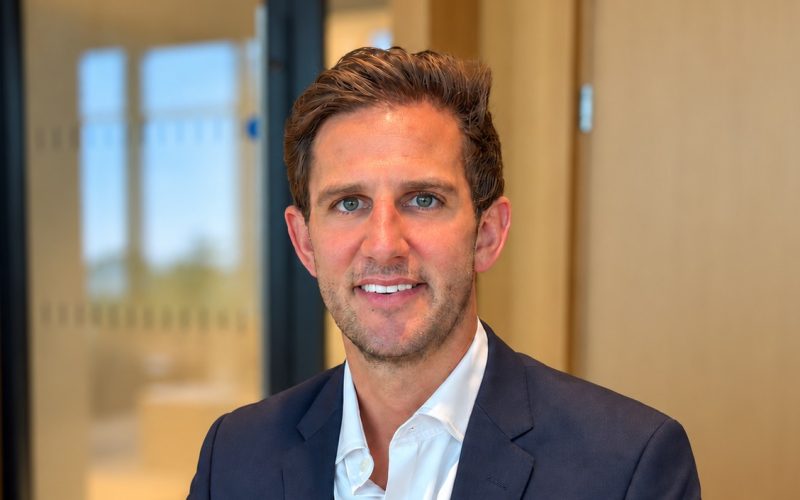 Charlie How, newly appointed Cushman & Wakefield partner, seated in an office wearing a navy suit.