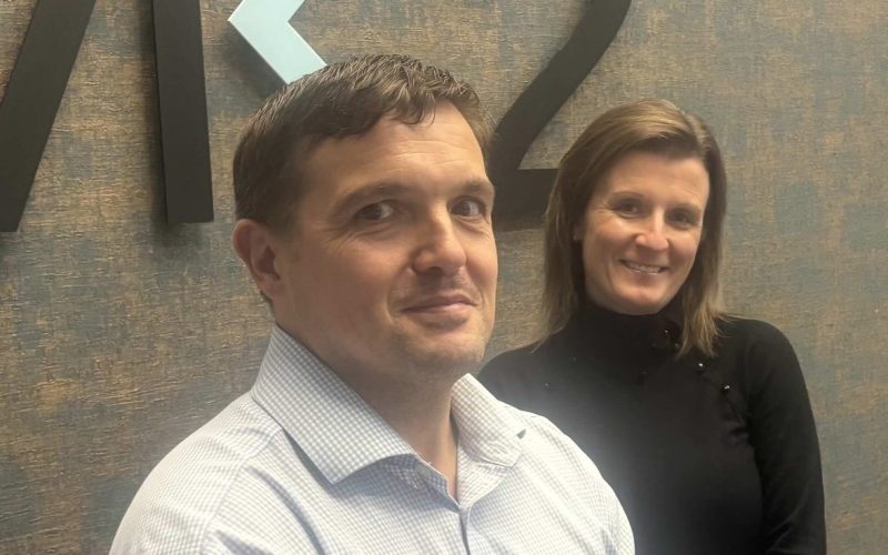 Vicky Round and a male colleague stand in front of the MK2 Real Estate logo.