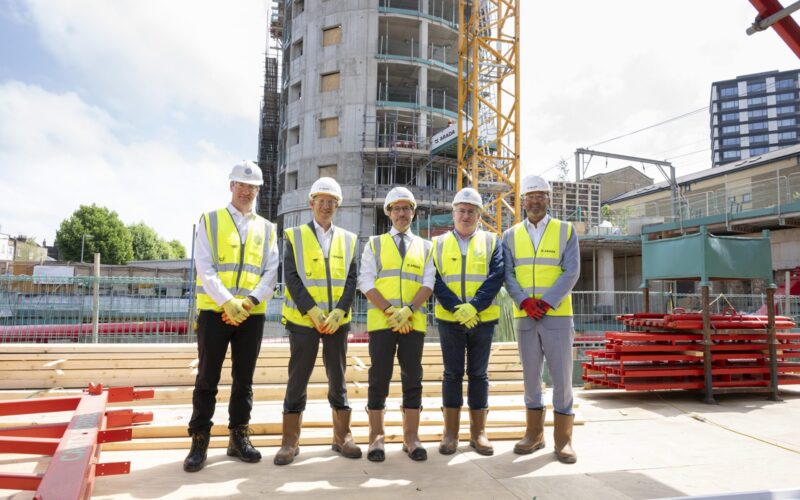Five men wearing high vis jackets and hard hats stood on a building site