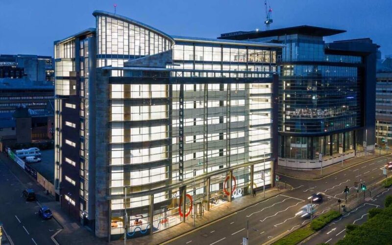 A multi-storey office building in Glasgow city centre with a modern facade, fully lit up at night