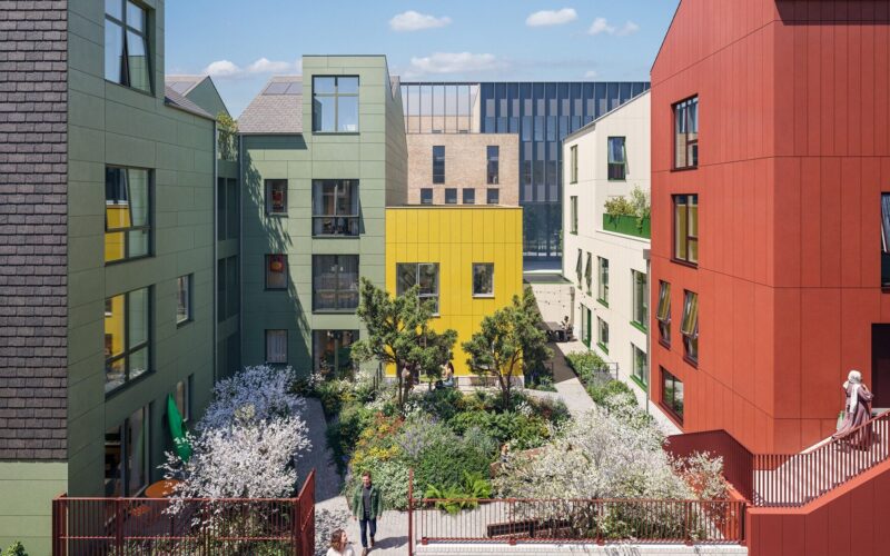 CGI of a series of different coloured residential buildings with a garden in the middle