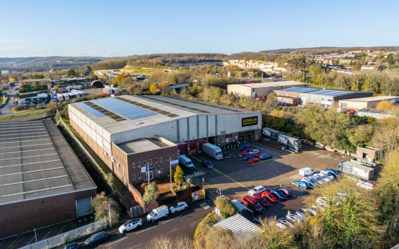 Aerial view of an industrial building with cars and vans parked in front