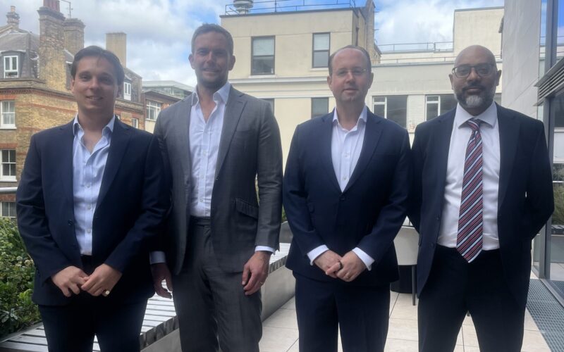 Four men stood side by side wearing suits