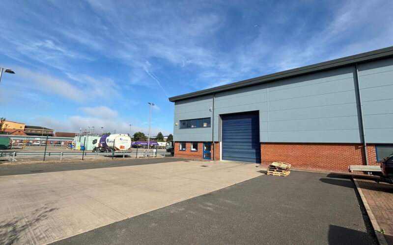A low rise industrial building with a large concrete yard