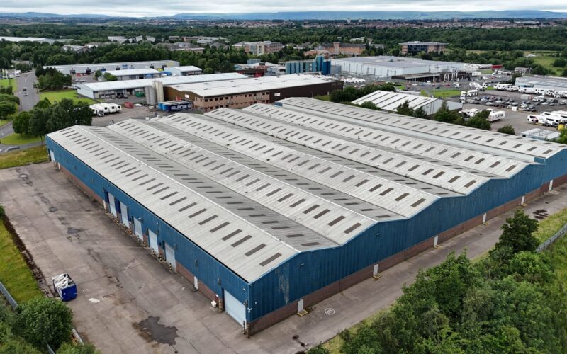 Aerial view of a large industrial building featuring peak roofs and blue walls