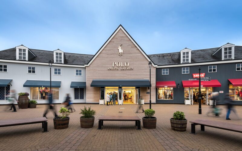 Low rise wooden cladded buildings with a Polo Ralph Lauren store in the middle