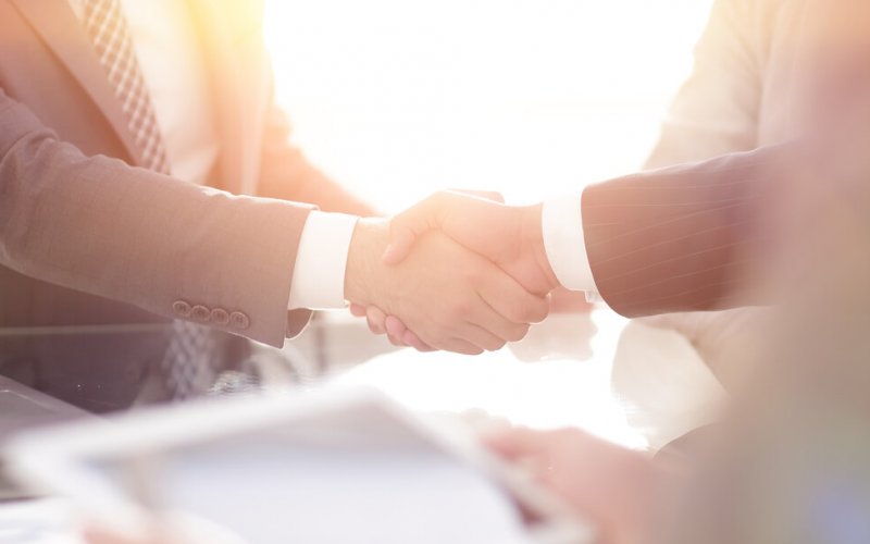 Two mean wearing suits shaking hands