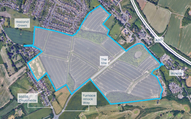 Aerial view of development land highlighted with a blue outline surrounded by houses and fields