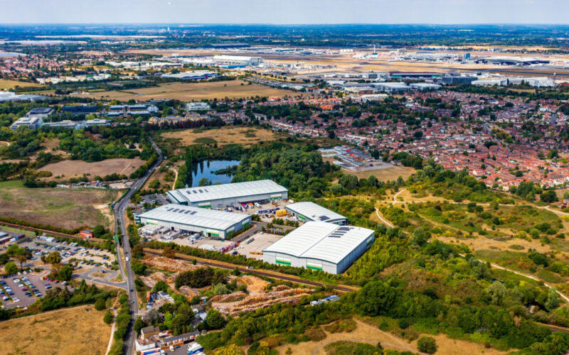 Four modern logistics units located on a site surrounded by grassland with Heathrow Airport in the distance