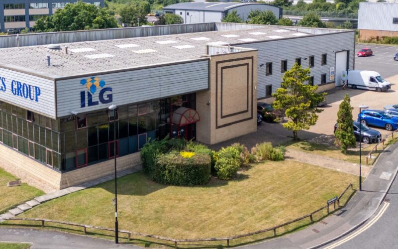 An old industrial building with car parking and green space to the front and side