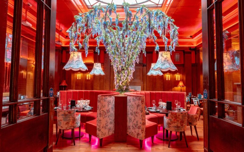 Luxurious interior of a restaurant featuring large chandeliers and red walls and furnishings