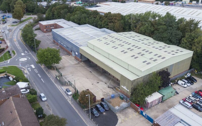 Aerial view of an old industrial building with a main road running alongside
