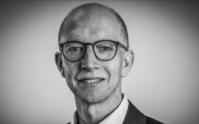 Black and white head and shoulders picture of a man wearing a suit