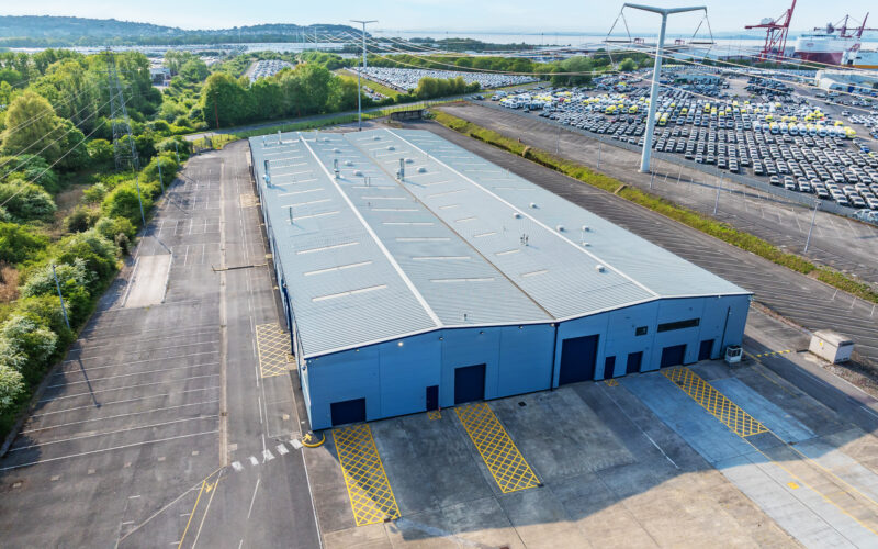 Aerial view of a large industrial building with lots of cars in the background