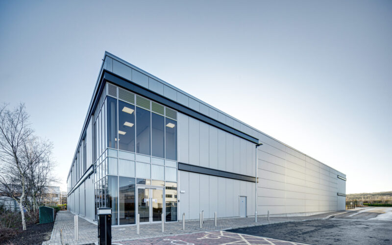 A modern low-rise warehouse building with a silver facade