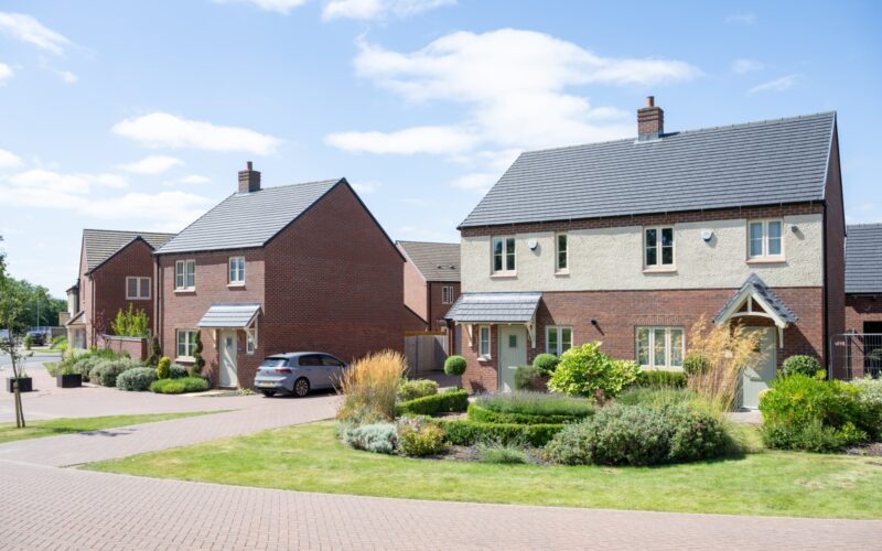 A row of modern new build houses with gardens and car parking to the front