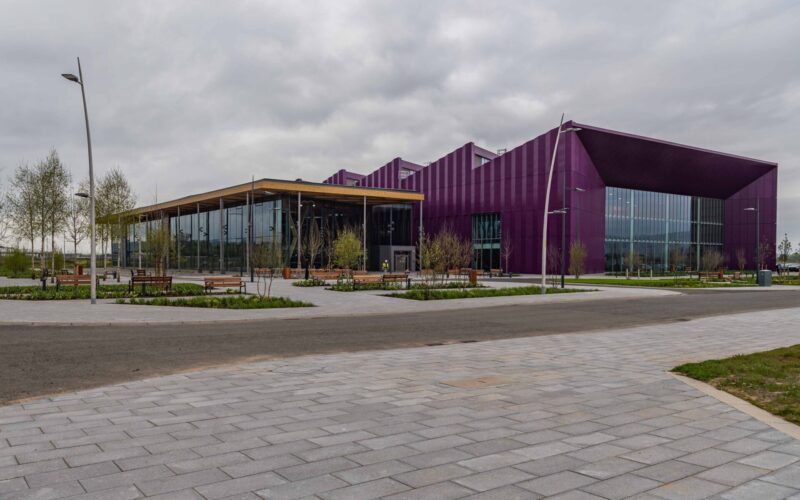 A low rise manufacturing facility with a large paved area in the foreground