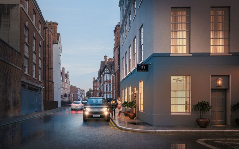 A series of buildings at dusk with a car parked on a corner