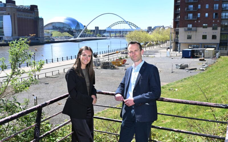 A white female stood to the left and a white male wearing a suit stood on Newcastle's Quayside