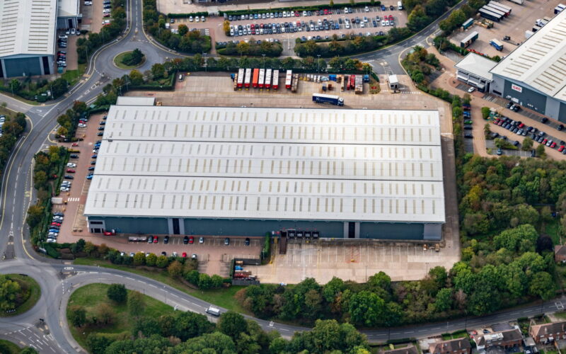 Aerial view of an industrial building surrounding by yard space and car parking