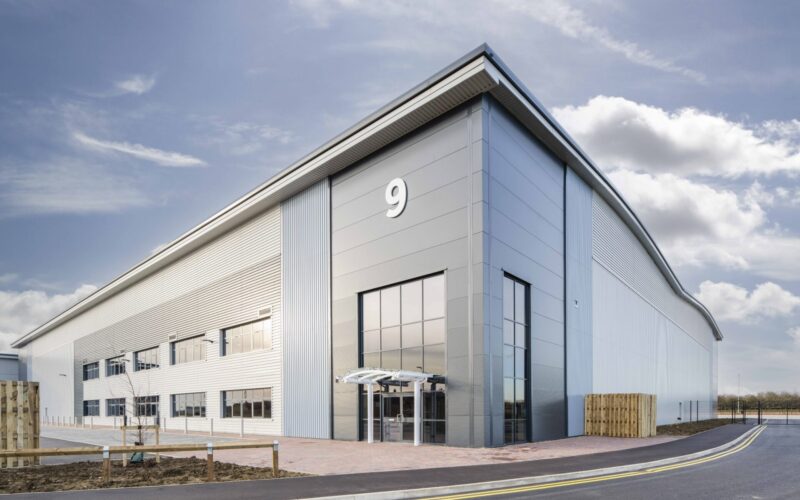 A modern steel clad warehouse featuring a series of windows on the corner and down the side
