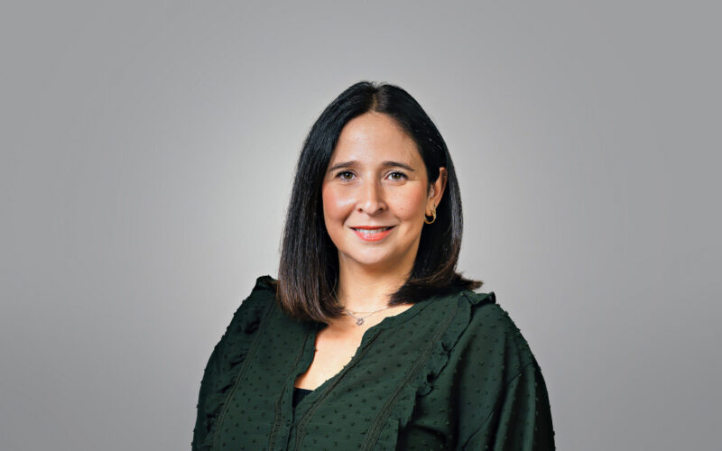 A smiling woman with shoulder-length dark hair wearing a dark green shirt