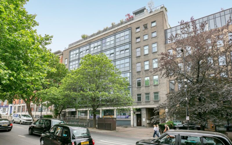 Exterior view of an office building with a tree-lined main road in front