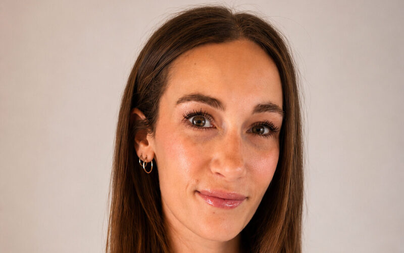A woman with long brown hair wearing a sleeveless top