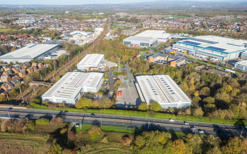 Aerial view of a series of industrial buildings at Stone Cross Park surrounding by trees and greenery