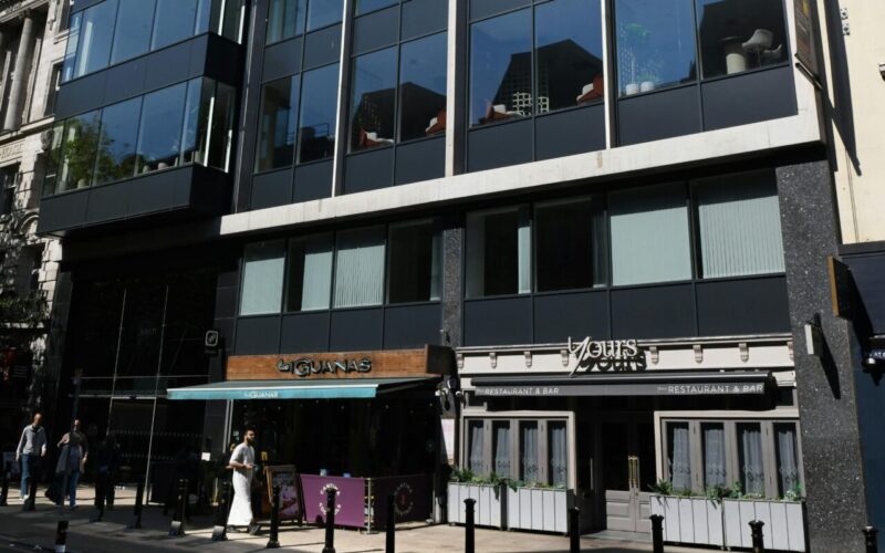 An office building with retail units on the ground floor and a main road in front