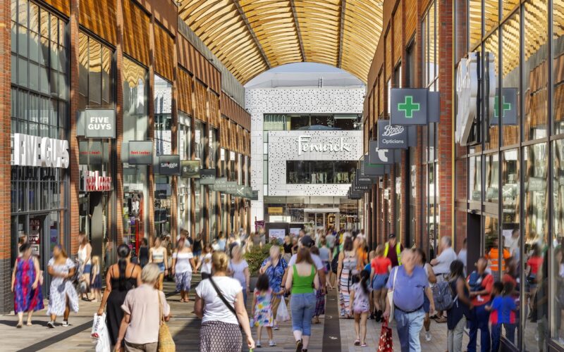 Shoppers walking down an arched street with retail stores on either side and a Fenwick store at the end of the street