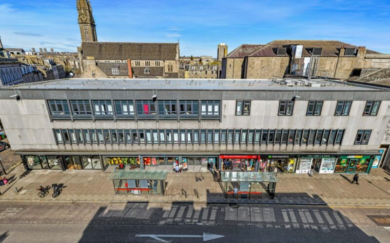A low rise retail parade in Aberdeen city centre with shops along the bottom of the building and rows of windows above