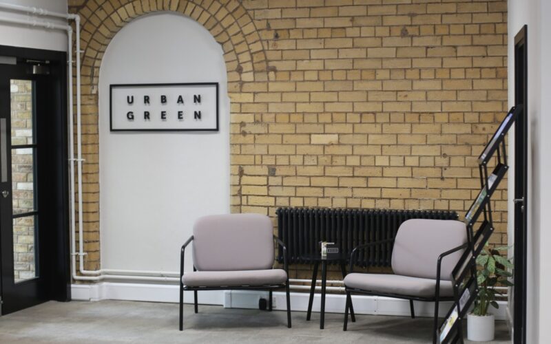 Entrance to an office building featuring an exposed brick wall and the Urban Green logo