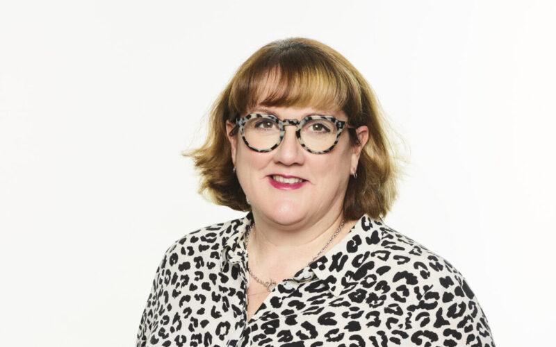 A woman with a brown bob hair cut wearing glasses and a patterned shirt