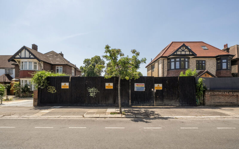 Hoardings between two residential buildings with a main road running in front