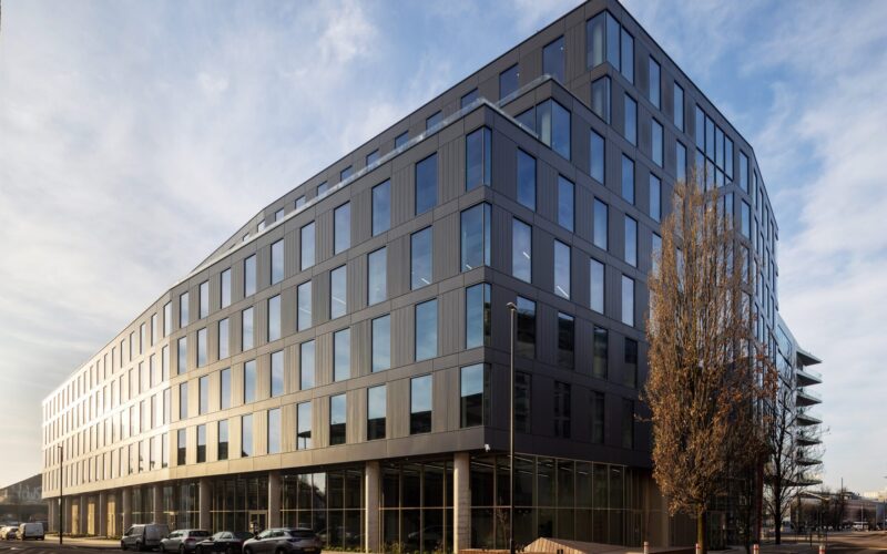 A striking, dark coloured modern office building with lots of windows to the side and front