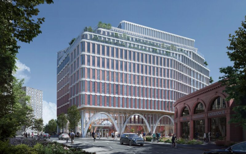 A modern office building featuring a glass and steel facade with a main road running in front